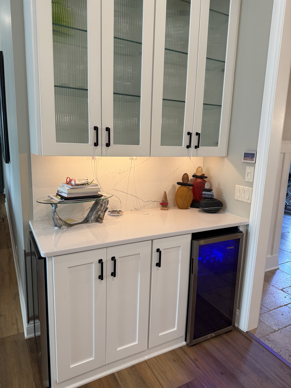 Refinished glass-front cabinets above a beverage fridge